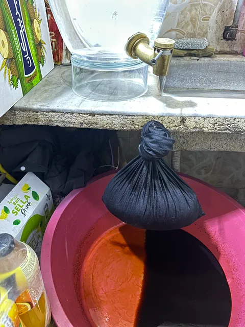 Cloth bag of fermented liquorice root dripping brew into a basin