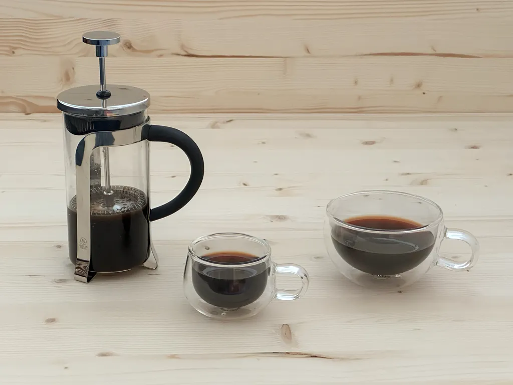 French press with brewed NooTea and two glass cups on a light wooden surface